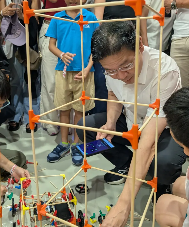 Prime Minister Lawrence Wong building a large chopstick cube with children