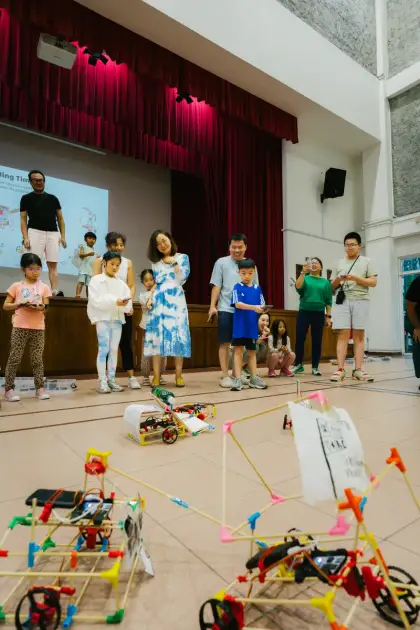 A family holds up their child's creation on stage
