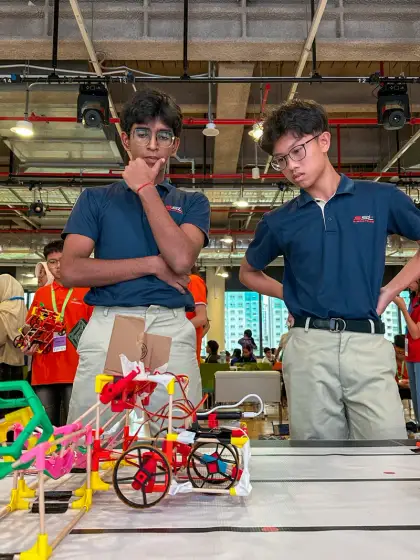 Two builders and their finished wheeled robot