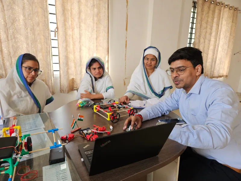 Teachers in India building robot cars at a table with a laptop