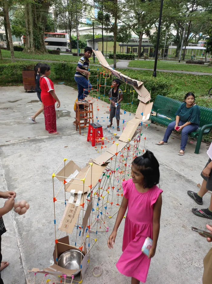 A child and an adult with a long chopstick bridge outdoors